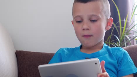 Smiling-boy-eating-snacks-while-using-tablet