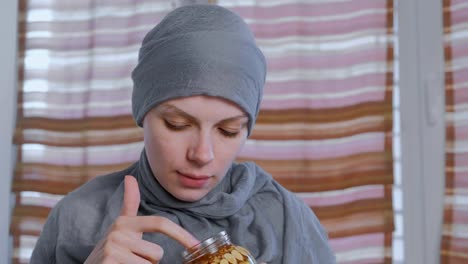 Muslim-woman-in-a-headscarf-dips-her-finger-in-honey-with-nuts-in-the-jar.-Eats-honey-from-finger.