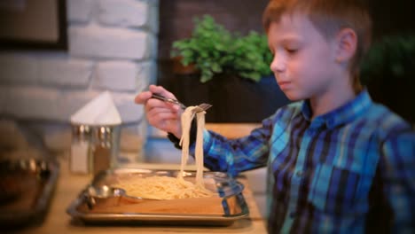 Niño-come-espaguetis-en-el-café-y-TV-de-relojes.