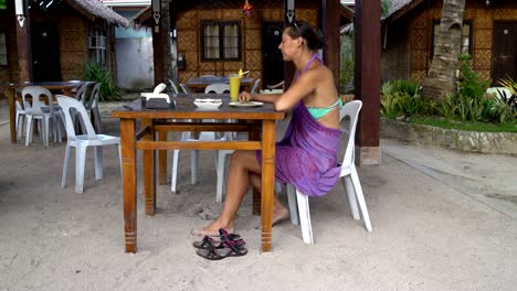 Una-mujer-se-sienta-en-una-mesa-en-el-restaurante,-come-y-bebe-cócteles