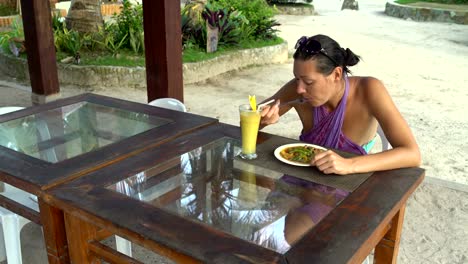 A-girl-sits-in-a-restaurant-on-the-street-and-eating-meat-with-vegetables