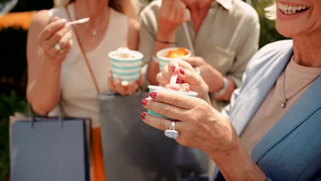 Mujeres-maduras-con-bolsas-de-compras,-comer-helado-en-la-ciudad