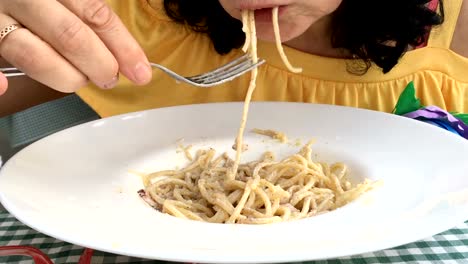 Mujer-en-un-vestido-amarillo-es-comer-una-pasta-con-salsa-blanca.