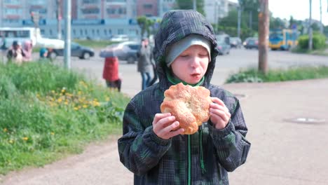 Junge-auf-der-Straße-eine-Brötchen-zu-essen.