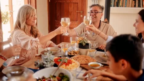 Während-dem-Mittagessen-zu-Hause-trinkt-mehr-Generationen-Familie-Toasten,-mit