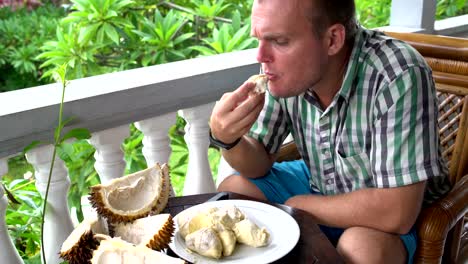 Ein-Mann-sitzt-auf-dem-Balkon-Essen-durian