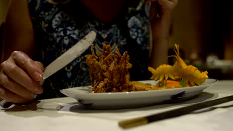 Caucasian-women's-hands-with-a-knife-and-fork-to-cut-meat-in-batter