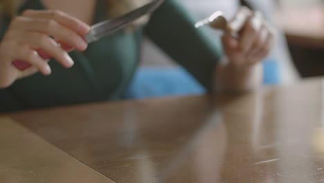 Restaurant-table-and-woman-hands-eating-steak