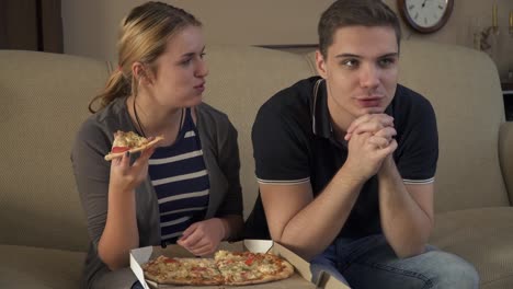 Young-couple-with-a-box-of-pizza-sits-on-the-couch