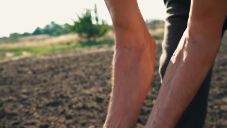 El-grano-está-en-manos-del-granjero,-trigo-se-vierte-a-través-de-los-dedos-del-hombre-en-el-campo