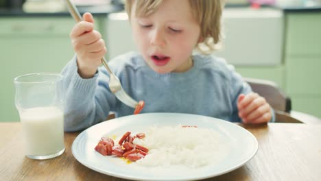 Niedliche-kleine-Junge-Chorizo-mit-Gabel-am-Tisch-essen