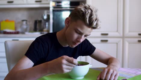 Niño-rubio-come-el-desayuno-en-la-cocina