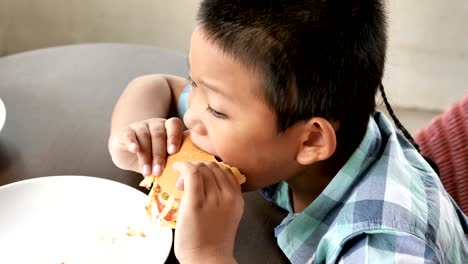 Lindo-muchacho-asiático-son-felices-comiendo-una-hamburguesa-en-restaurante.-Video-4k-lenta