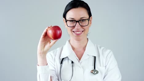 portrait-of-a-nutritionist,-an-expert-on-food-and-health-welfare,-smiles-looking-into-camera-and-holding-an-apple-on-a-white-background.