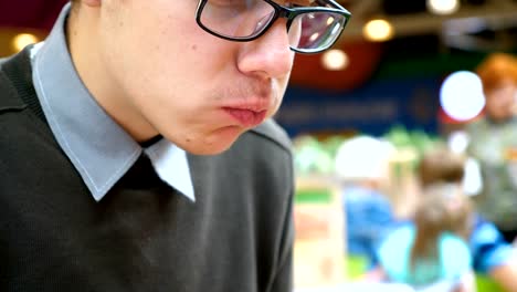 A-young-man-is-eating-a-hamburger-in-a-shopping-center.