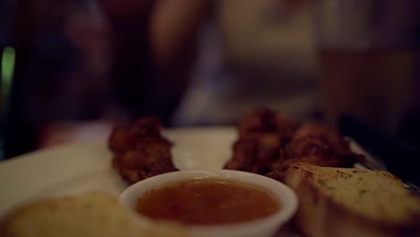 Young-Asian-traveling-women-backpacker-drinking-alcohol-or-beer-with-friends-and-eating-food,-snack-and-chicken-wings-in-urban-street-night-party-at-restaurants-in-Bangkok,-Thailand.