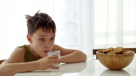 Junge-Essen-hausgemachte-Kekse-mit-Milch-in-der-Küche-zu-Hause.