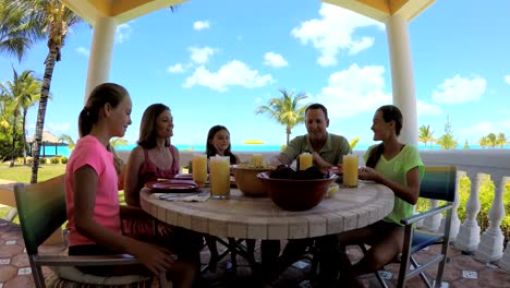 Caucasian-family-dining-on-vacation-beach-hotel-decking