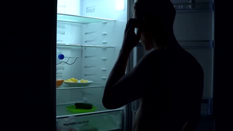 Hungry-man-is-looking-for-food-to-eat-in-fridge-at-night.-Unhealthy-food-concept