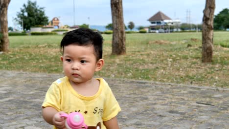 Asiatischen-Jungen-zu-Fuß-und-hält-eine-Flasche-Milch-in-den-Park-im-freien