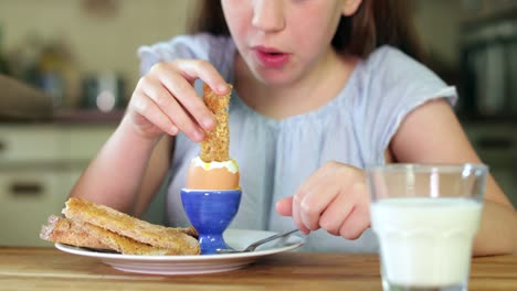 Nahaufnahme-von-Mädchen-essen-gesunde-gekochtes-Ei-und-braun-Toast-zum-Frühstück-In-der-Küche