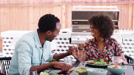 Joven-pareja-negra-sentado-en-mesa-fuera-riendo