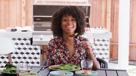 Junge-schwarze-Frau-Essen-Mittagessen-an-einem-Tisch-im-Garten