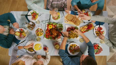 Gran-familia-y-fiesta-de-amigos-en-casa,-grupo-diverso-de-personas-se-reunieron-en-la-mesa,-brindar-en-un-brindis.-Gente-comiendo,-bebiendo-y-divirtiéndose-en-la-sala-de-estar.-Arriba-hacia-abajo-por-encima-de-tiro.