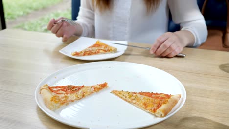 Pizzeria.-Junge-Frau-nimmt-ein-Stück-Pizza-in-ihrem-Teller