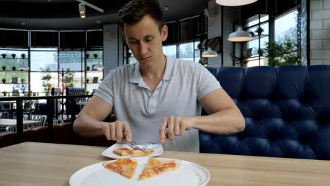 Young-handsome-man-eating-pizza-at-a-cafe