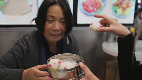 Frauen-Touristen-genießen-niedliche-Schwein-geformt-Dim-Sum-in-einem-Restaurant-in-Hongkong