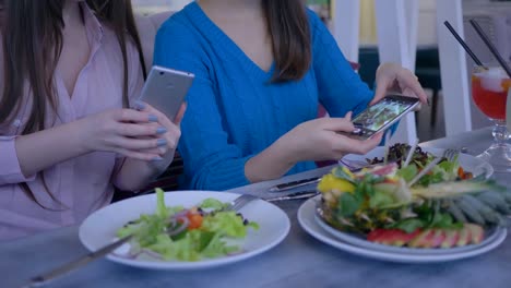 Händen-der-Frauen-Freunde-mit-Handy-für-Foto-des-schönen-Salat-während-gesundes-Abendessen-während-Diät-zur-Gewichtsreduktion-in-restaurant