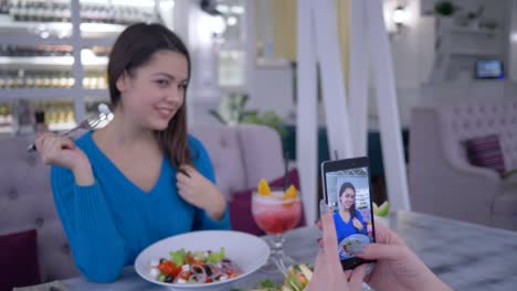 Portrait-von-vegetarischen-Frau-mit-frischen-nützlich-Salat-in-der-Hand-fotografiert-auf-Handy-für-soziale-Medien-während-des-Mittagessens-im-restaurant