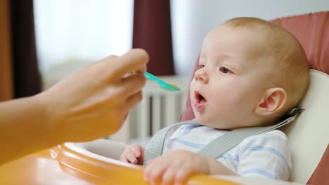 Niedliche-Baby-in-den-Stuhl-zu-Hause-essen