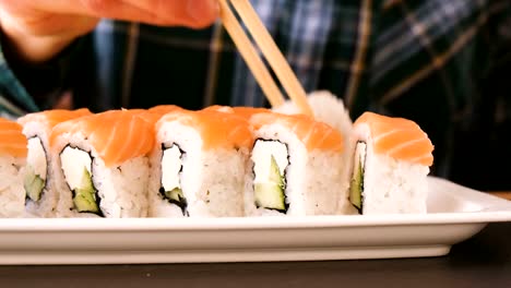 Man-eats-rolls-with-chopsticks-in-a-restaurant-close-up