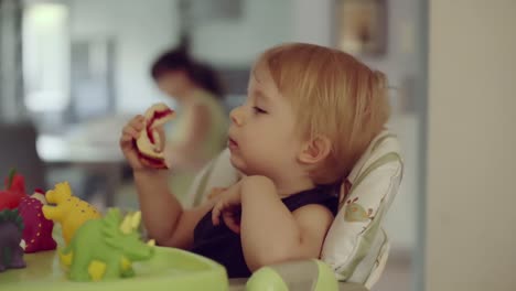 kleiner-Junge-sitzt-auf-Hochstuhl-Sandwich-zu-essen