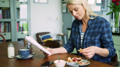 Schöne-blonde-Frau-Lesung-während-des-Essens-Frühstück