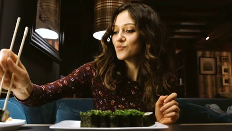 Schöne-Frau-kaukasischen-Essen-Sushi-in-ein-japanisches-Restaurant-und-etwas-interessantes-erzählt-seiner-Freundin-gegenüber