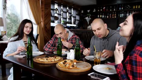 Spaß-im-Restaurant-Pizza-essen-und-Bier-zu-trinken.-Zwei-Jungs-und-zwei-Mädchen-in-der-Pizzeria.