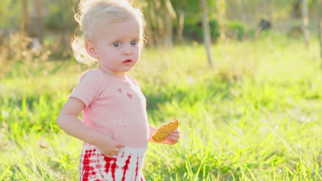 Cute-blonde-Kleinkind-draußen-in-der-Sonne-mit-cracker