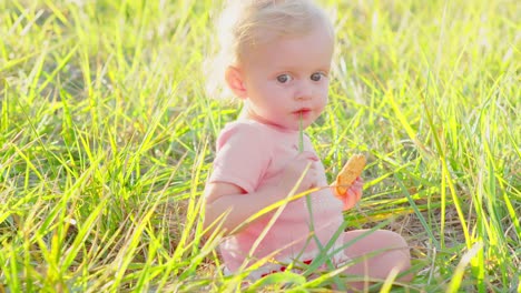 Cute-blonde-Kleinkind-draußen-in-der-Sonne-mit-cracker