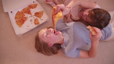 Girls-lying-on-the-floor-sharing-some-take-away-pizza