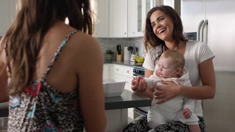 Pareja-femenina-en-la-cocina-con-su-niña-en-rodilla,-tiro-de-R3D