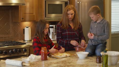 Family-making-homemade-pizza-together-in-the-kitchen