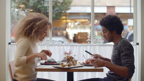 Pareja-joven/esposos-disfrutando-comida-en-fecha-en-restaurante-de-la-ciudad