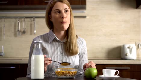 Beautiful-young-attractive-businesswoman-eating-cornflakes-for-breakfast-in-kitchen.-Cup-of-coffee