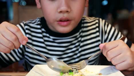 Young-asian-boy-eating-food-at-home-.