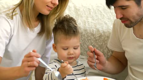 Kleine-entzückende-Junge-feiert-seinen-Geburtstag-fütterung-seinen-Vater-und-Mutter-mit-Kuchen