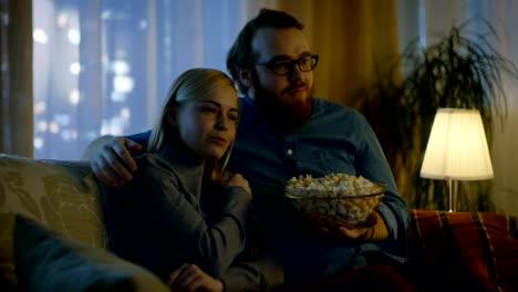 Couple-Watching-TV.-They-Sit-on-a-Sofa-in-Their-Cozy-Living-Room-and-Eat-Popcorn.-It's-Evening.