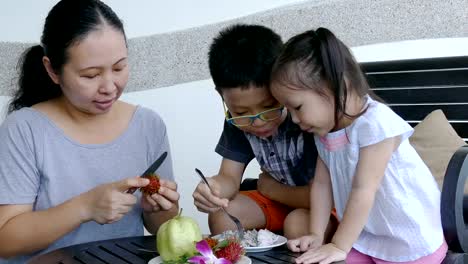 Los-niños-y-madre-comiendo-frutas-en-mesa